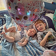 Bralor is registered to the contest to win money with this photo: baby, balloon, bed, blanket, blue, casual_clothing, child, cozy, cute, happy, heart, indoor, playful, red_hair, siblings, smile, striped_blanket, toddler, valentine, white