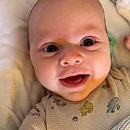 Sorley is registered to the contest to win money with this photo: baby, blanket, child, closeup, clothing, cozy, cute, expression, eyes, face, happy, indoors, infant, lying, newborn, onesie, person, skin, smile, soft