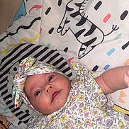 Maeve joined the competition — help win amazing prizes! baby, infant, headband, floral, patterned_clothing, blanket, cartoon, zebra, cute, child, lying_down, reaching, colorful, playful, soft_toys, indoor, smiling, face, closeup, young_child