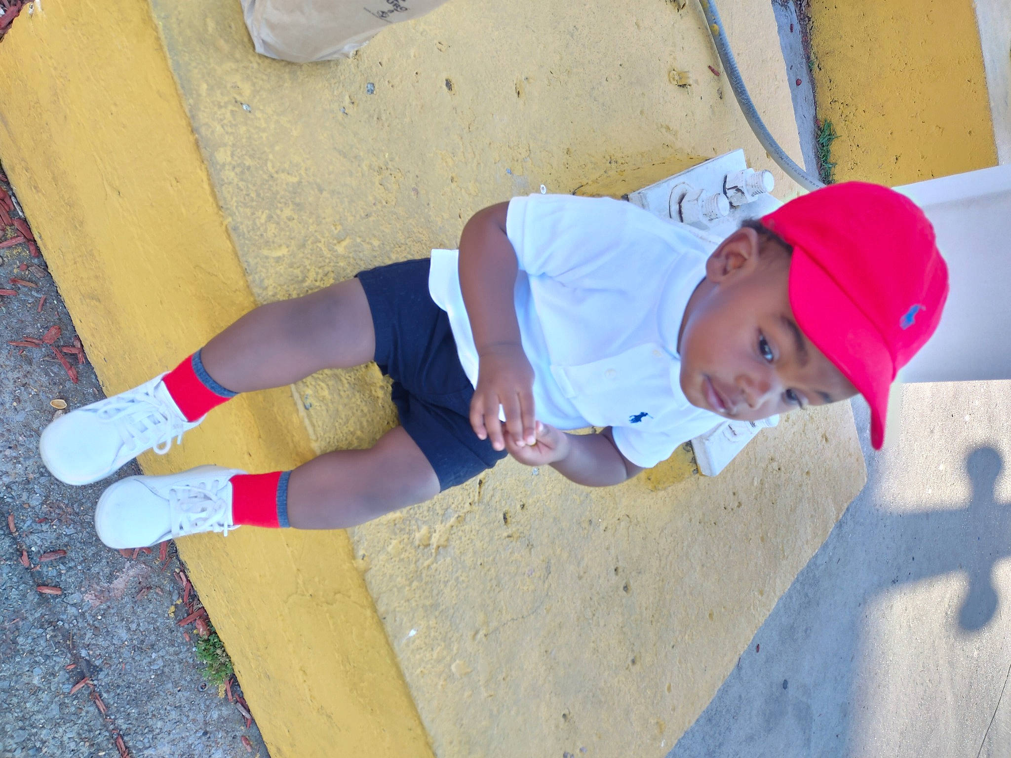 Gary joined the competition — help win amazing prizes! asphalt, baby, baseball_cap, child, concrete, foot, fun, hat, headwear, human_leg, knee, leg, leisure, person, recreation, sand, shorts, sidewalk, sitting, t_shirt