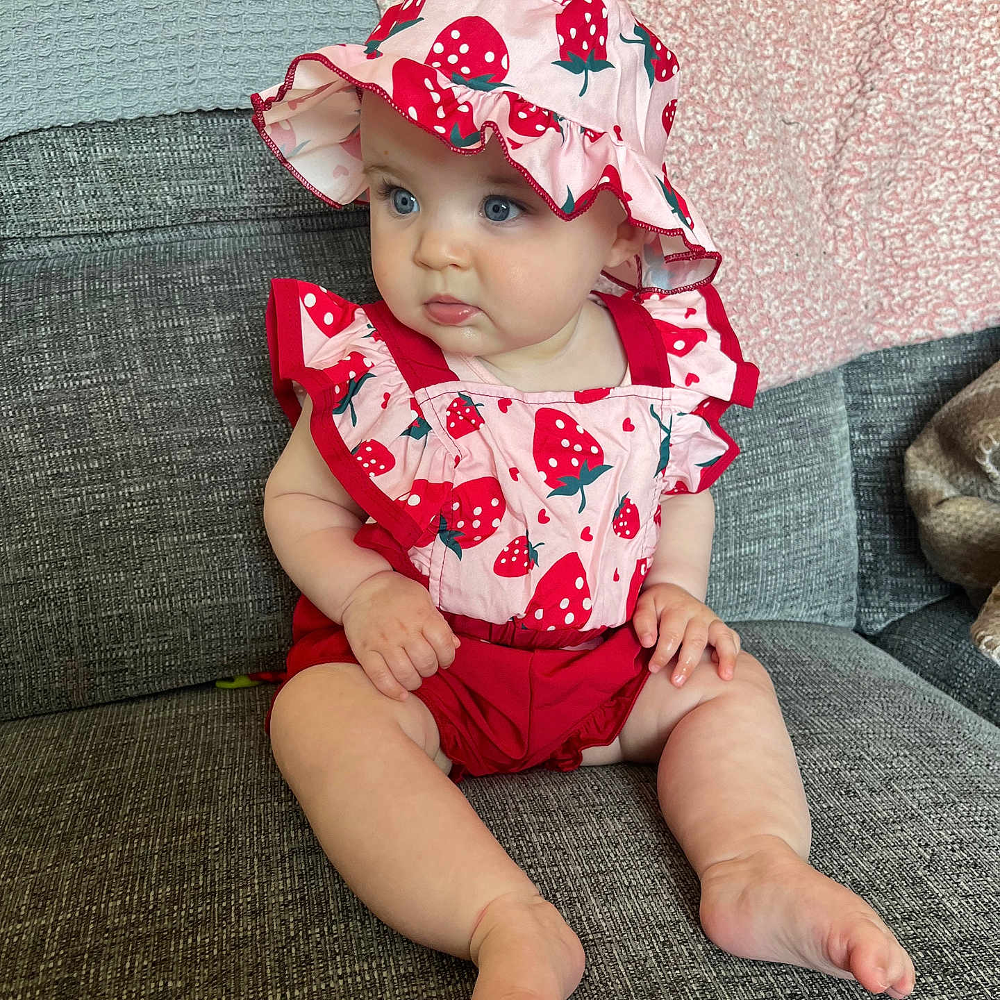 Gracie is registered to the contest to win money with this photo: baby, bonnet, cap, clothing, costume, couch, cushion, dress, face, furniture, hat, head, homedecor, pants, person, photography, portrait, shorts, sitting, sunhat