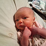Annabelle Austin is registered to the contest to win money with this photo: baby, newborn, infant, pink_clothing, bed, blanket, hand, face, skin, person, portrait, sleepwear, cute, resting, indoors, expression, young_child, small_hands, closeup, lying_down