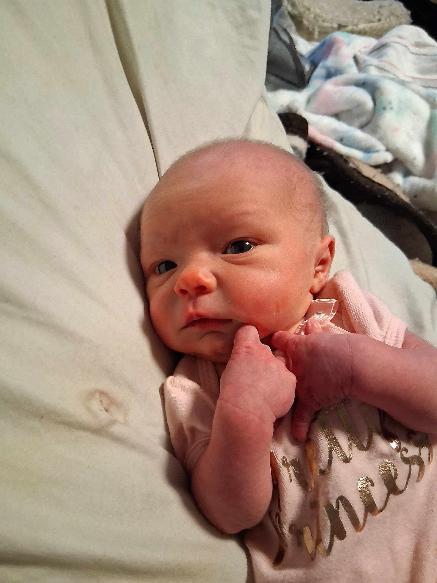 Annabelle Austin is registered to the contest to win money with this photo: baby, newborn, infant, pink_clothing, bed, blanket, hand, face, skin, person, portrait, sleepwear, cute, resting, indoors, expression, young_child, small_hands, closeup, lying_down