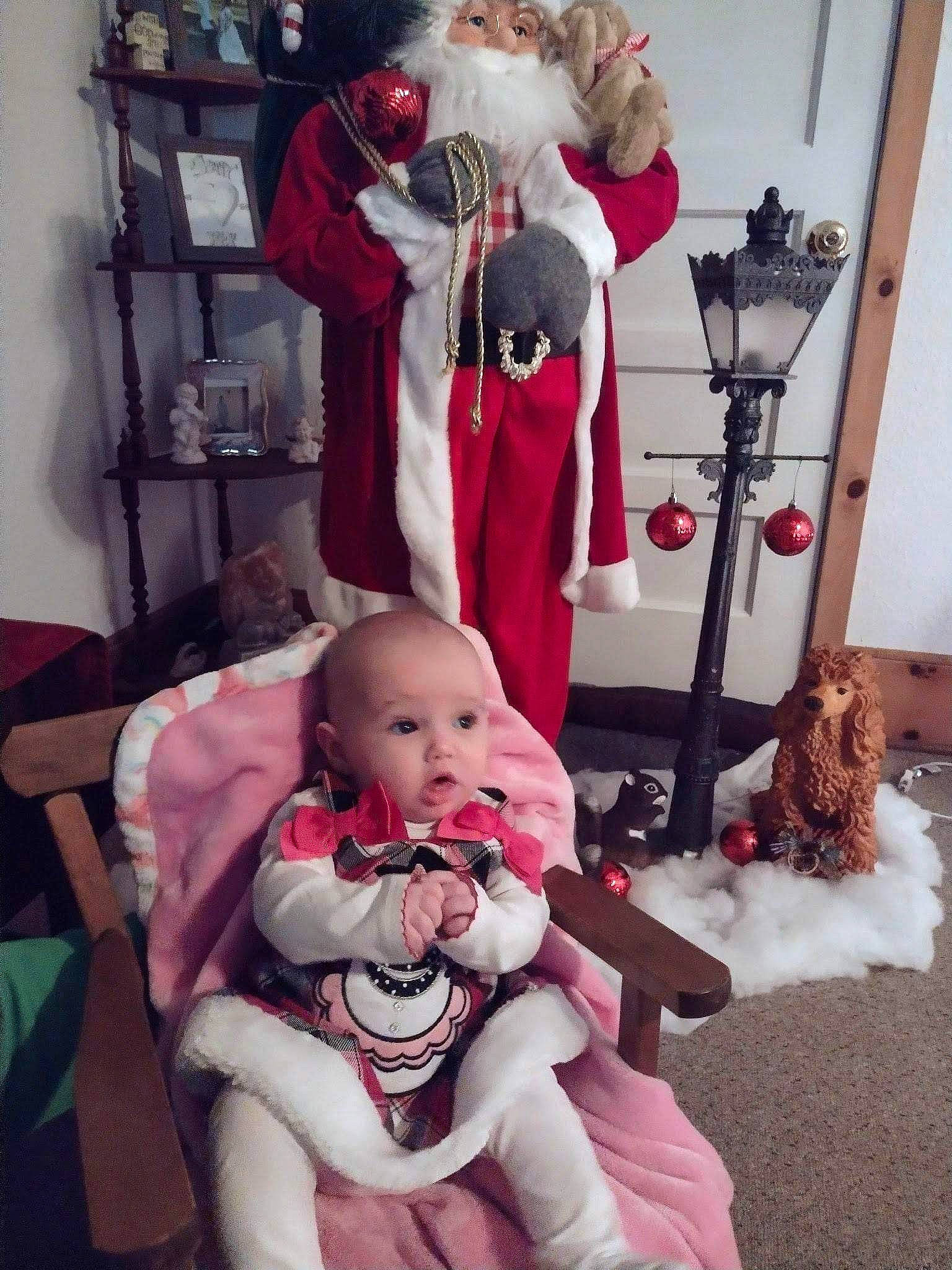 Journee is registered to the contest to win money with this photo: baby, carmine, chair, child, christmas_eve, comfort, event, fictional_character, fun, fur, holiday, lap, person, pink, red, room, santa_claus, sitting, surprise, textile