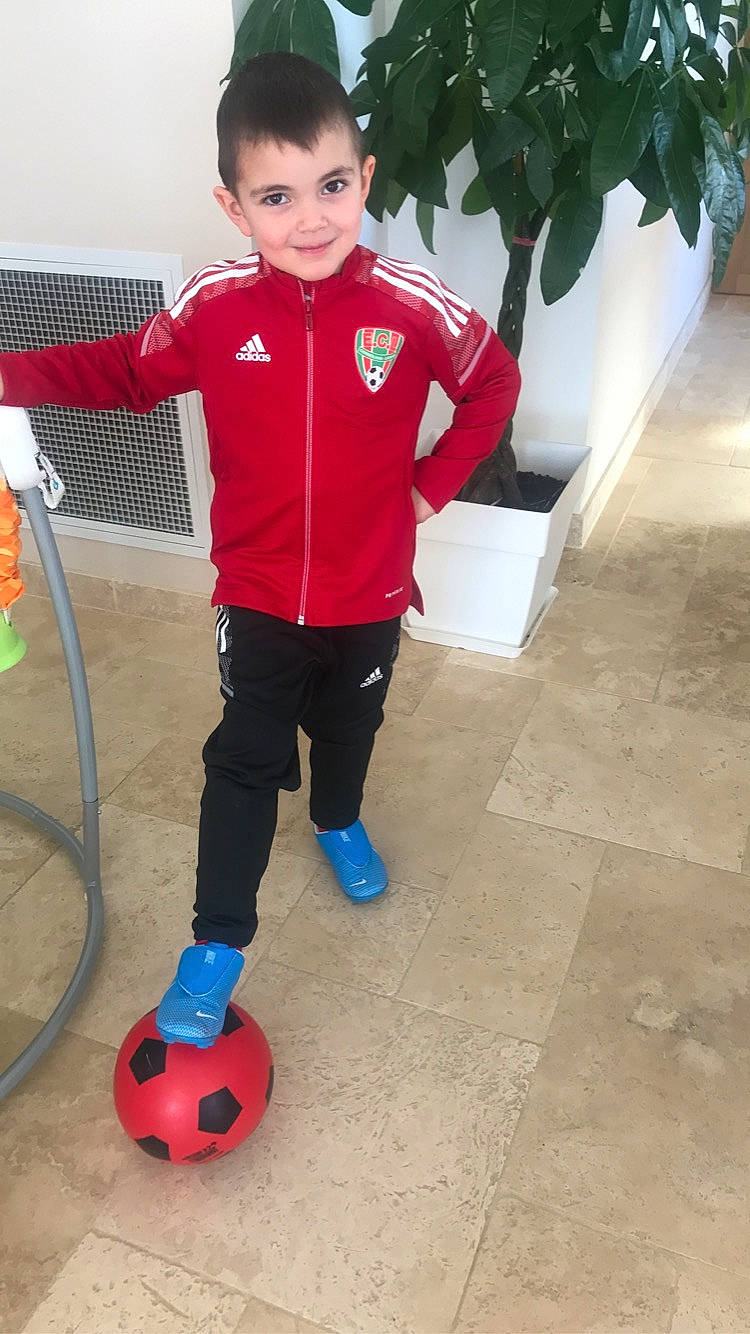 Tiago participe au concours pour gagner de l'argent avec cette photo : arm, ball, child, electric_blue, flooring, football, footwear, joy, person, plant, playing_sports, shorts, sleeve, smile, soccer, sports, sports_equipment, sportswear, standing, sweatpant