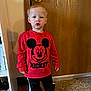 Tobias joined the competition — help win amazing prizes! toddler, child, indoor, red_sweatshirt, mickey_mouse, shoes, carpet, wooden_door, standing, clothing, casual, person, young_child, expression, floor, door_knob, pants, footwear, sleeves, portrait