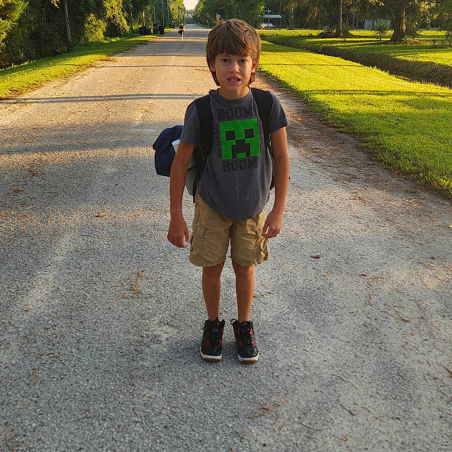 Wayne is registered to the contest to win money with this photo: boy, child, clothing, face, grass, head, nature, outdoors, pants, park, path, person, photography, plant, portrait, road, shorts, tree, vegetation, walking