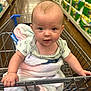 baby, shopping_cart, blanket, aisle, store, supermarket, infant, clothing, hand, face, expression, shelf, product, paper_towels, floor, looking_at_camera, grocery_store, cute, seated, shopping