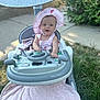 baby, child, baby_walker, pink_hat, pink_clothing, blanket, grass, outdoor, sidewalk, toy_steering_wheel, happy, smiling, sunhat, person, seat, greenery, summer, cute, infant, playtime
