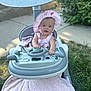 baby, child, baby_walker, hat, pink_clothing, blanket, outdoor, grass, pavement, toy_steering_wheel, sun_hat, person, infant, seat, play, cute, smiling, summer, greenery, sunlight