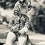 baby, black_and_white, blocks, bonnet, child, clothing, concrete, curious, cute, daylight, hat, holding, leopard_print, outdoor, person, portrait, sitting, stick, toddler, young_child