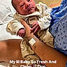Zion Luciano joined the competition — help win amazing prizes! newborn, baby, infant, hospital, hospital_room, parent, adult, holding, cradling, face, portrait, onesie, blanket, medical_equipment, hospital_bed, tattoo, wristband, seated, indoor, text_overlay