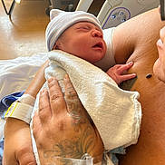 Zion Luciano joined the competition — help win amazing prizes! newborn, baby, infant, hospital, parent, mother, father, skin_to_skin, swaddled, blanket, knit_hat, sleeping, crying, face, hand, tattoo, medical, hospital_bed, wristband, portrait