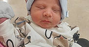 Zion Luciano is registered to the contest to win money with this photo: newborn, baby, infant, sleeping, portrait, face, hat, knit_hat, clothing, onesie, blanket, bundled, peaceful, indoors, close_up, sitting, caregiver, patterned, soft_lighting, photography