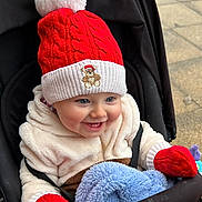 Alfie is registered to the contest to win money with this photo: baby, child, smiling, hat, mittens, stroller, blanket, winter_clothing, outdoor, happy, blue_eyes, red_hat, red_mittens, cozy, cute, infant, portrait, warm_clothing, baby_clothes, seatbelt