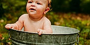 Sawyer is registered to the contest to win money with this photo: baby, child, metal_tub, outdoor, nature, greenery, grass, leaves, wet_hair, curious, playful, skin, infant, summer, daylight, portrait, sitting, cute, young, bare_chested