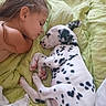 affection, animal, bed, bedding, child, close_up, cuddling, dalmatian, dog, girl, green_blanket, indoors, lying_down, person, pet, portrait, puppy, sleeping, spotted_dog, tender