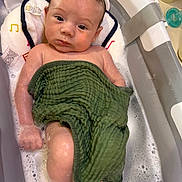 Louis is registered to the contest to win money with this photo: baby, infant, child, bathtub, bath, bubbles, towel, green_towel, wet_hair, face, eyes, portrait, indoors, bathroom, soap, pacifier, water, relaxed, sitting, photography