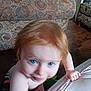 toddler, child, red_hair, blue_eyes, indoor, couch, patterned_fabric, wooden_floor, hand, grip, curious, skin, bare_shoulders, home, carpet, person, furniture, blur, closeup, expression