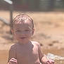 toddler, child, water, beach, sand, wet_hair, red_swim_trunks, sunlight, smiling, outdoor, summer, playing, happy, sitting, bare_chest, young_child, vacation, fun, nature, portrait