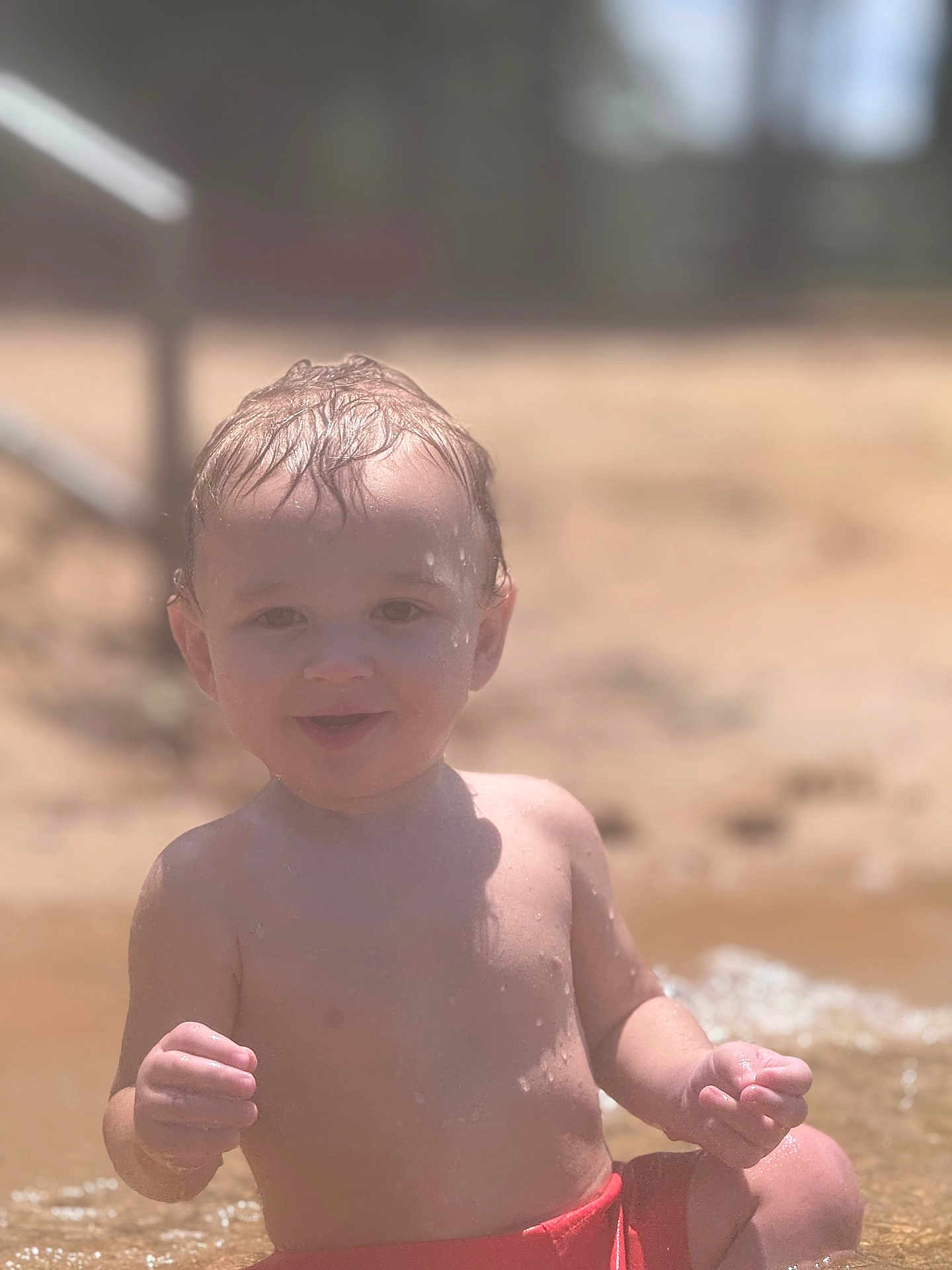 Nathon joined the competition — help win amazing prizes! toddler, child, water, beach, sand, wet_hair, red_swim_trunks, sunlight, smiling, outdoor, summer, playing, happy, sitting, bare_chest, young_child, vacation, fun, nature, portrait