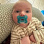 baby, pacifier, blue_eyes, striped_pajamas, cushion, indoor, tile_floor, infant, closeup, child, person, cozy, cute, comfort, hands, face, expression, looking_up, soft_light, home