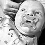 baby, pacifier, hand, tattoo, black_and_white, blanket, pattern, infant, face, portrait, closeup, person, skin, expression, newborn, cute, care, support, gentle, looking_up