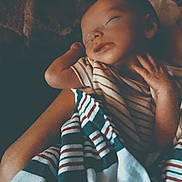 Gage Ridings joined the competition — help win amazing prizes! baby, sleeping, blanket, striped_clothing, arm, peaceful, infant, person, rest, comfort, portrait, cozy, hands, soft_light, indoor, closeup, toddler, young_child, warmth, care