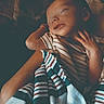 baby, sleeping, blanket, striped_clothing, arm, peaceful, infant, person, rest, comfort, portrait, cozy, hands, soft_light, indoor, closeup, toddler, young_child, warmth, care