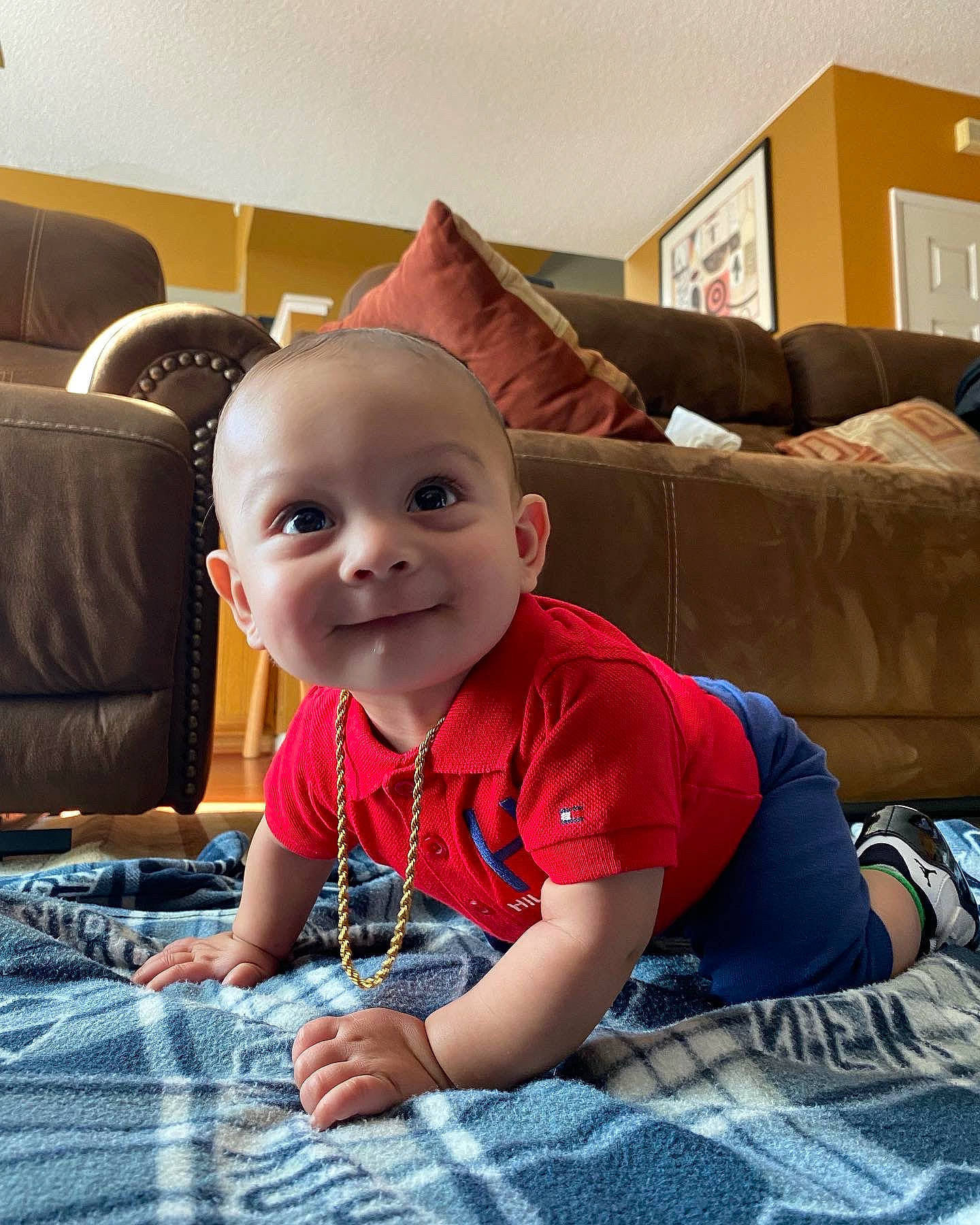 Jamal is registered to the contest to win money with this photo: baby, child, comfort, couch, eye, floor, flooring, fun, furniture, happy, head, joy, living_room, person, picture_frame, plaid, room, sitting, smile, t_shirt