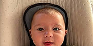 Elio a rejoint le concours — aidez-le/la à gagner de superbes lots ! baby, infant, smile, face, seat, baby_seat, straps, toy, crochet_toy, clothing, green_outfit, indoors, child, happy, head, person, closeup, cute, home, baby_accessory