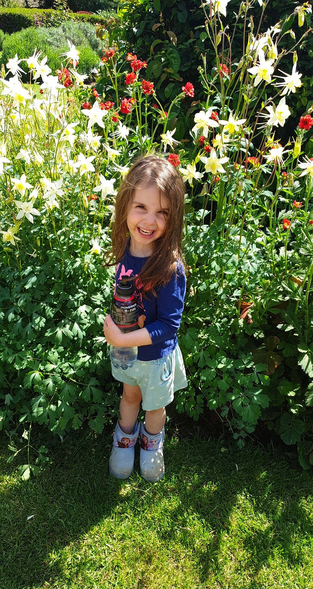 Aurora is registered to the contest to win money with this photo: annual_plant, baby_toddler_clothing, botany, flower, flowering_plant, garden, grass, groundcover, happy, herbaceous_plant, joy, leaf, meadow, people_in_nature, person, petal, plant, rose_family, shorts, shrub