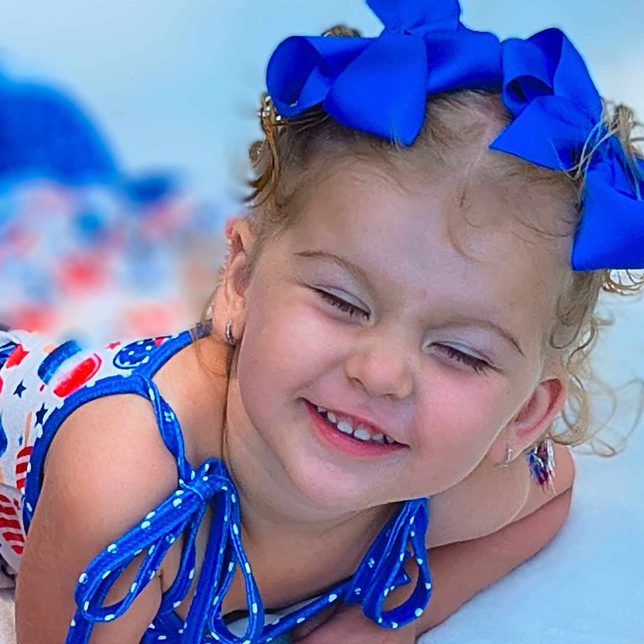 Serinaty joined the competition — help win amazing prizes! child, toddler, smiling, blue_bow, curly_hair, happy, face, portrait, clothing, earrings, skin, hand, lying_down, summer, colorful, cute, outdoor, closeup, person, joyful