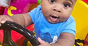Onyx joined the competition — help win amazing prizes! baby, blue_shirt, cartoon_character, child, colorful, curious, expression, face, fun, hands, indoor, person, plastic, play_area, red, seat, steering_wheel, toy, yellow, young