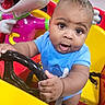 Onyx joined the competition — help win amazing prizes! baby, child, toy, steering_wheel, blue_shirt, indoor, play_area, colorful, plastic, cartoon_character, expression, face, hands, seat, yellow, red, fun, curious, young, person