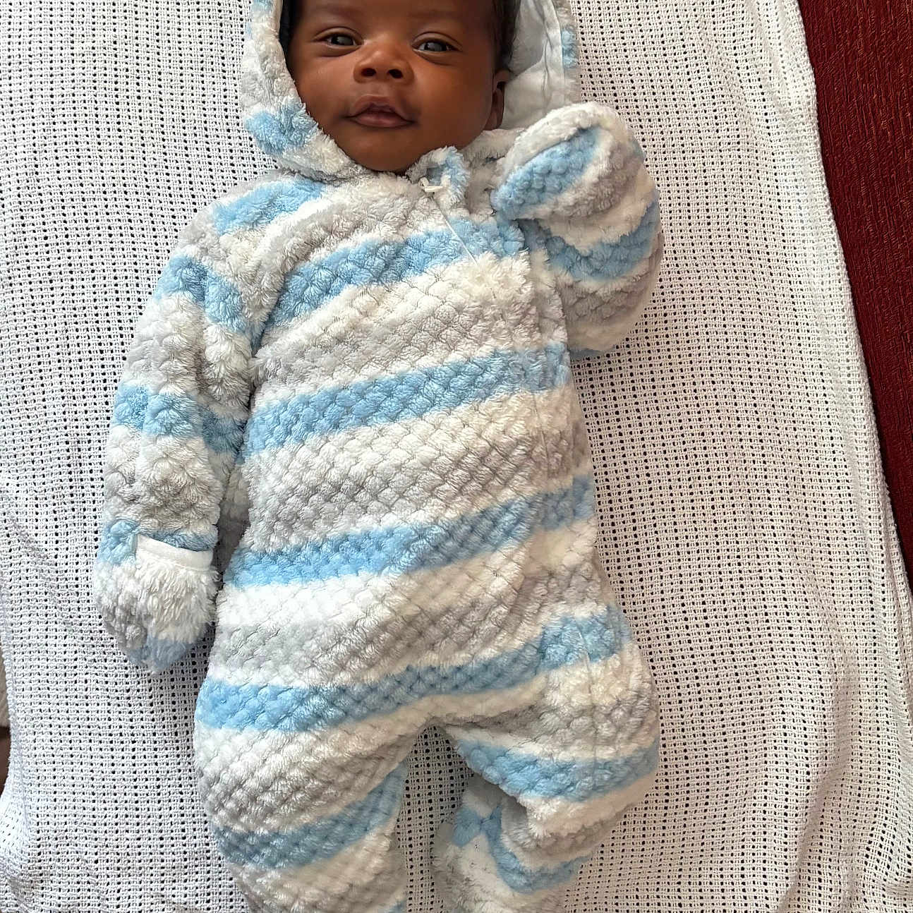 Chidubem joined the competition — help win amazing prizes! apparel, baby, blanket, blue, child, cozy, cute, face, hooded, indoors, infant, lying_down, newborn, onesie, person, smiling, soft, striped, warm, white