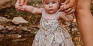 Saylor joined the competition — help win amazing prizes! baby, child, pink_bow, floral_dress, holding_hands, legs, water, stream, outdoor, nature, adult, shorts, sandals, feet, rock, grass, summer, cute, support, exploration