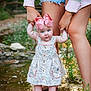Saylor is registered to the contest to win money with this photo: baby, child, blue_eyes, pink_bow, floral_dress, barefoot, water, creek, holding_hands, adult, legs, nature, outdoor, grass, rocks, stream, summer, smiling, cute, support
