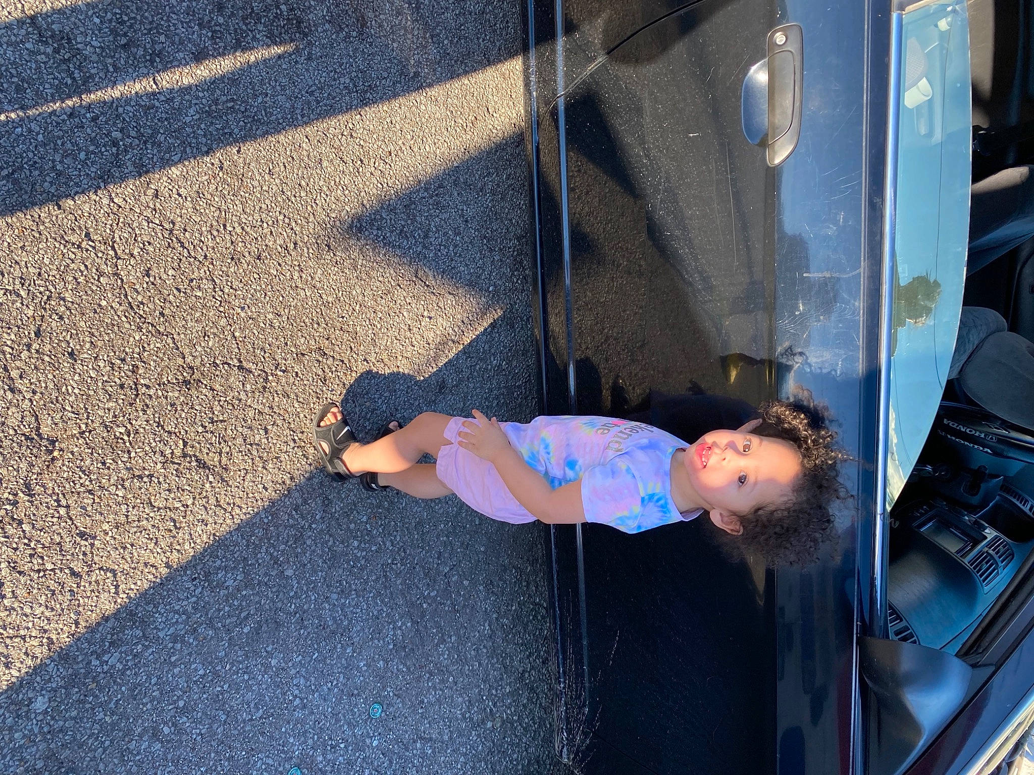 Aubrey is registered to the contest to win money with this photo: asphalt, auto_part, automotive_exterior, automotive_lighting, automotive_tire, automotive_window_part, bumper, concrete, electric_blue, flooring, hood, human_leg, leisure, motor_vehicle, person, road_surface, sidewalk, tints_and_shades, toddler, vehicle_door