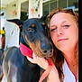 Demon Lee is registered to the contest to win money with this photo: woman, dog, doberman, portrait, selfie, pet, animal, collar, leash, face, outdoor, porch, blurred_background, red_collar, hand, closeup, companion, friendship, calm, bond