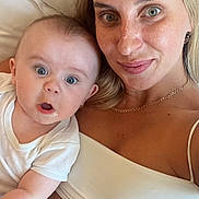Alexandre participe au concours pour gagner de l'argent avec cette photo : baby, woman, freckles, blonde_hair, white_shirt, pillow, cuddle, closeup, face, smile, expression, indoor, skin, person, parent, child, portrait, bed, casual, happy