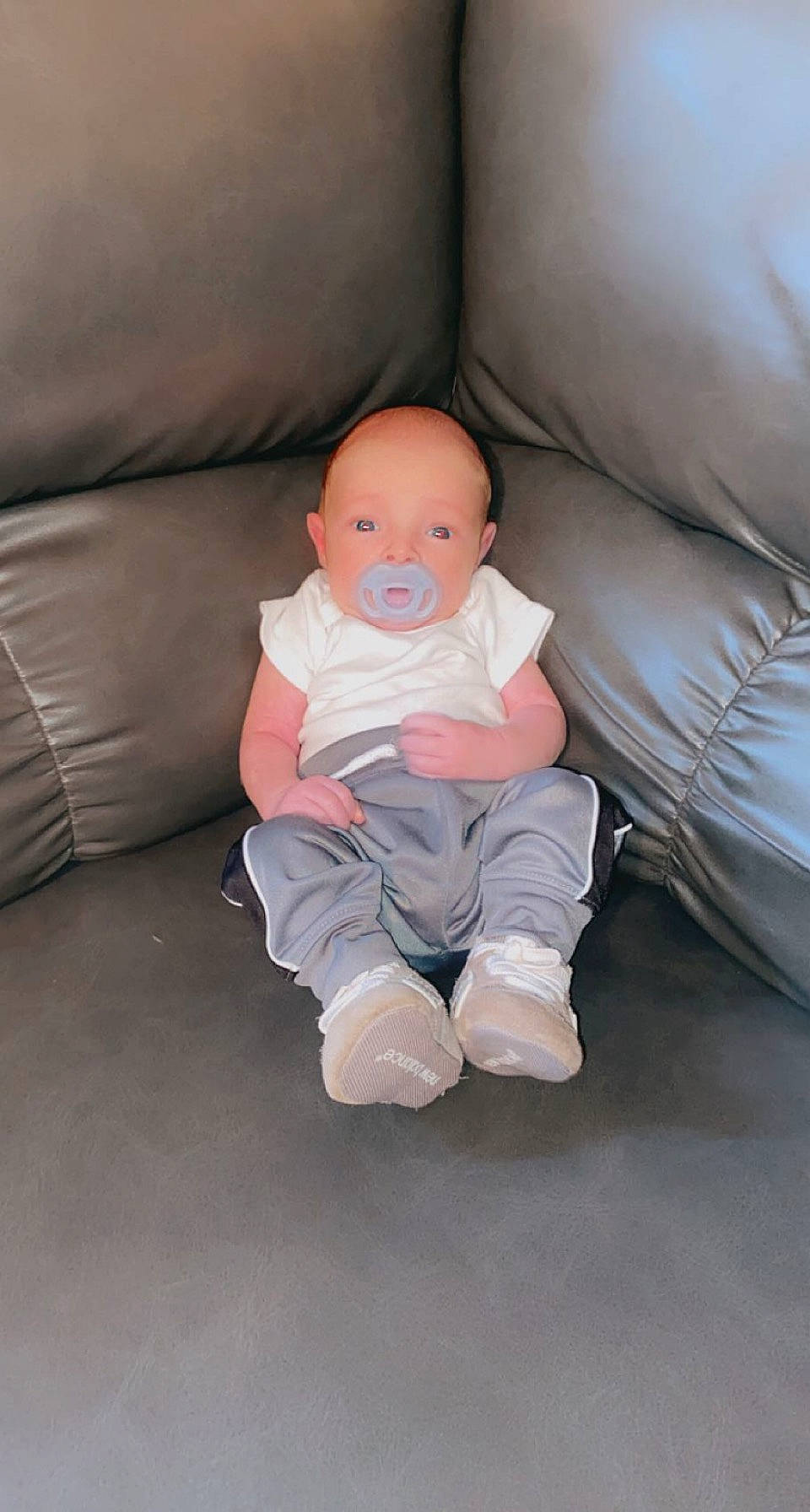 Koby is registered to the contest to win money with this photo: baby, baby_toddler_clothing, cheek, child, comfort, couch, eye, floor, flooring, foot, fun, hardwood, knee, leg, person, room, sitting, sleeve, t_shirt, toddler