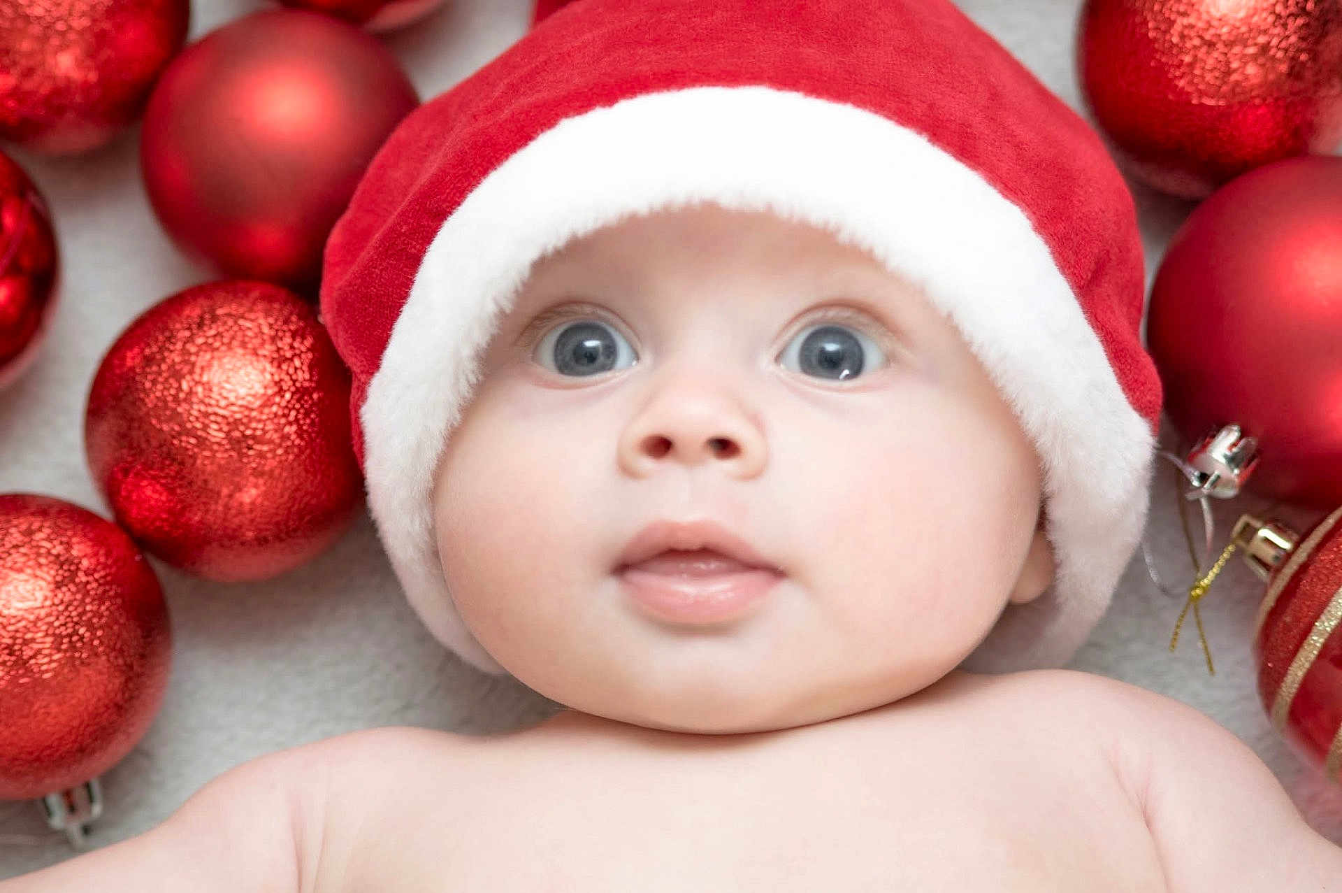 Rowan joined the competition — help win amazing prizes! baby, face, santa_hat, christmas_ornaments, red, white, blue_eyes, holiday, festive, cute, infant, closeup, skin, expression, cheeks, mouth, background, decorations, celebration, portrait