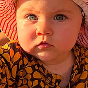 Léna a rejoint le concours — aidez-le/la à gagner de superbes lots ! baby, child, face, blue_eyes, hat, striped_hat, sunlight, close_up, curious, patterned_clothing, yellow, brown, outdoor, portrait, young_child, infant, cute, expression, headwear, person