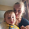 child, toddler, woman, indoor, portrait, face, expression, yellow_shirt, clothing, curtain, window_light, hair, person, closeup, casual, family, parent_and_child, young_child, real_people, intimate_moment