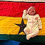 Lael is registered to the contest to win money with this photo: baby, infant, onesie, headband, smiling, lying_down, colorful_flag, red, yellow, green, black_star, fabric, textile, cuteness, peaceful, newborn, child, indoors, soft, portrait