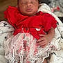 baby, child, sleeping, red_clothing, lace, floral_pattern, blanket, cozy, hand, infant, cute, portrait, indoor, soft_texture, peaceful, rest, newborn, fabric, toddler, wrapped
