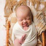 Grayson is registered to the contest to win money with this photo: newborn, baby, smiling, tongue_out, wrapped, blanket, wicker_basket, cozy, infant, cute, sleeping, soft, skin, hands, feet, portrait, closeup, peaceful, child, indoors