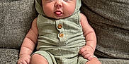 Grayson is registered to the contest to win money with this photo: baby, infant, child, couch, furniture, clothing, romper, hood, shoes, tongue, cute, expression, sitting, indoors, texture, fabric, person, skin, legs, hands