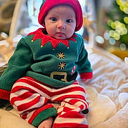 Lily participe au concours pour gagner de l'argent avec cette photo : baby, child, infant, elf_costume, holiday_outfit, red_and_white_stripes, green_fleece, hat, cute, sitting, indoors, soft_blanket, festive, christmas, portrait, face, person, cozy, warm_lighting, decor